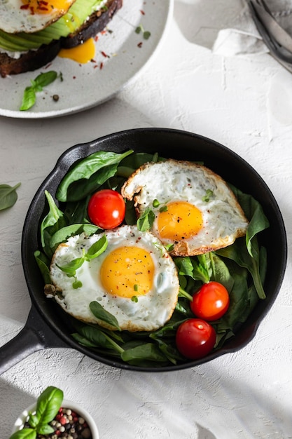 Breakfast with fried eggs and vegetables in a pan