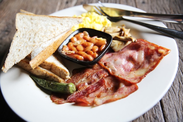 Breakfast with ham , fried egg and bread on wood background low key