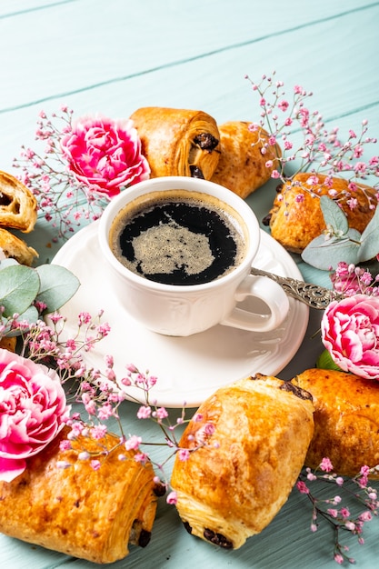 Breakfast with mini fresh croissants bun with chocolate and coffee cup on blue turquoise surface. Copy space