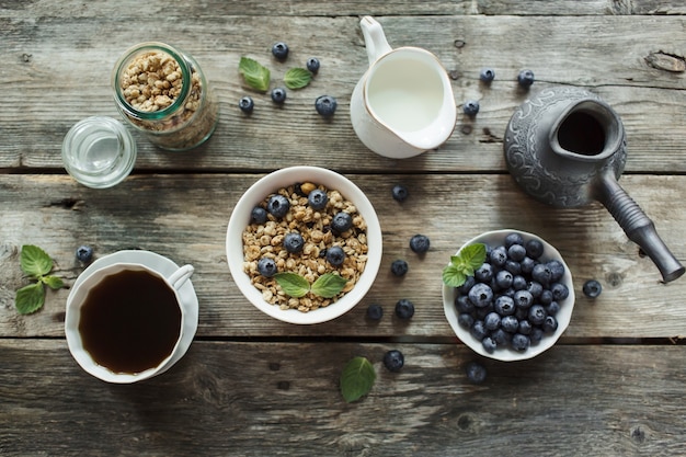 ミューズリー、新鮮なベリーブルーベリー、木の背景にコーヒーと朝食。健康食品のコンセプト。フラットレイ、上面図。