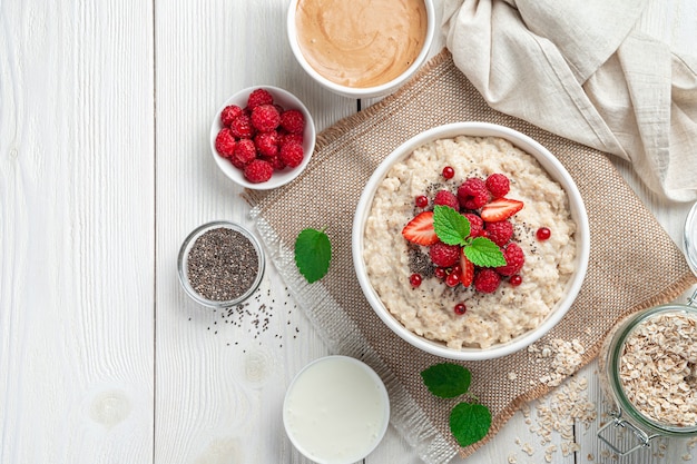 Breakfast with oatmeal with healthy berries and chia seeds on a light background