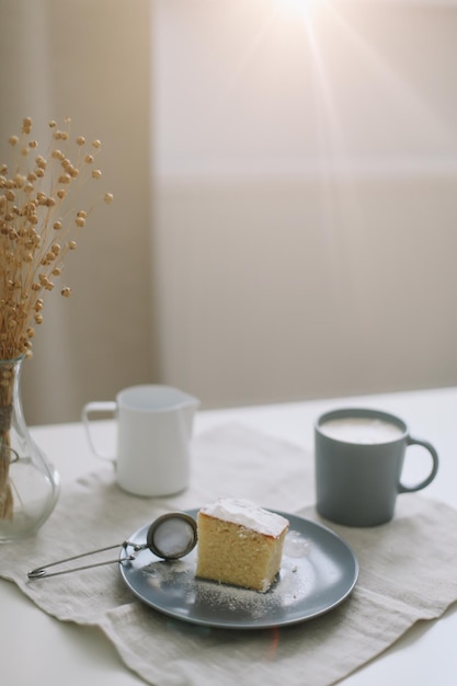 Breakfast with a piece of fresh homemade cake pitcher and cup of coffee on a table