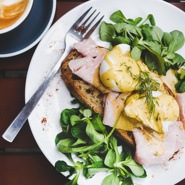 Breakfast with poached eggs on bread with ham square crop