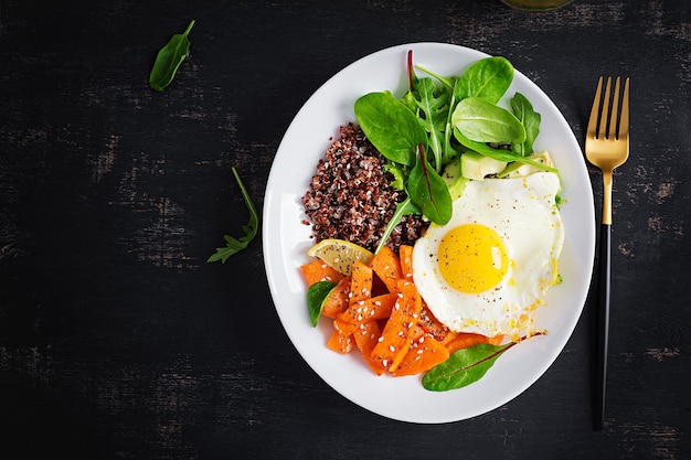 Colazione con quinoa, fette di zucca fritte, avocado e uovo fritto