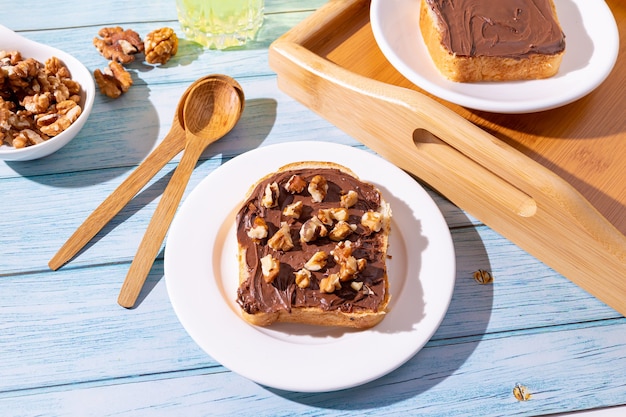 breakfast with sandwiches with chocolate paste and walnuts on a light blue background