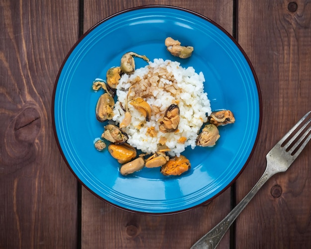 Foto colazione con frutti di mare e riso su un piatto blu in piedi su un tavolo di legno