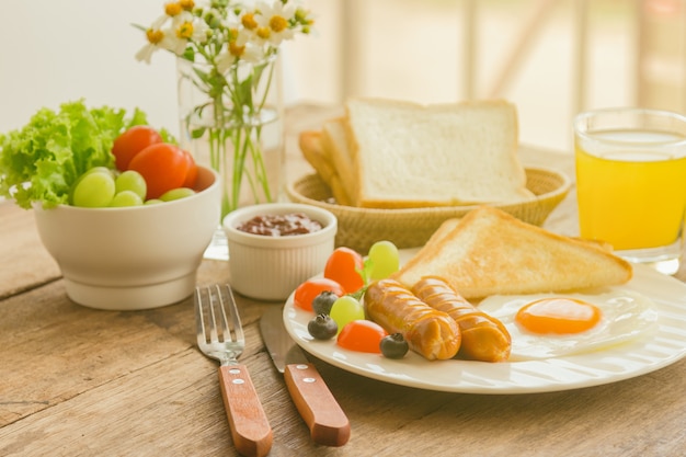 Breakfast with sunny side up fried egg toast sausage fruit vegetable strawberry jam