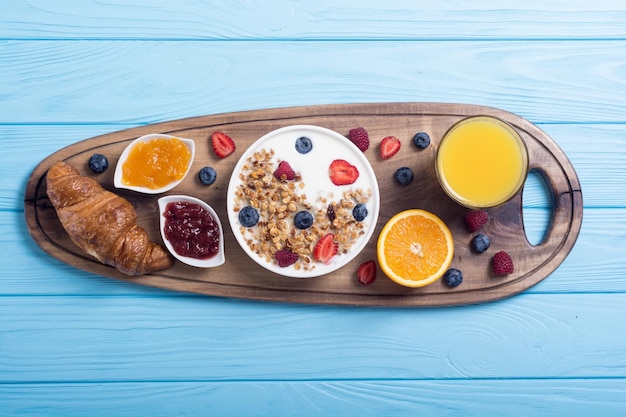 Photo breakfast with yogurt granola berries orange juice croissant and jam