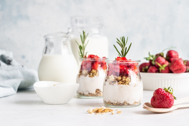 Faccia colazione con yogurt, granola e la fragola fresca in un barattolo di muratore