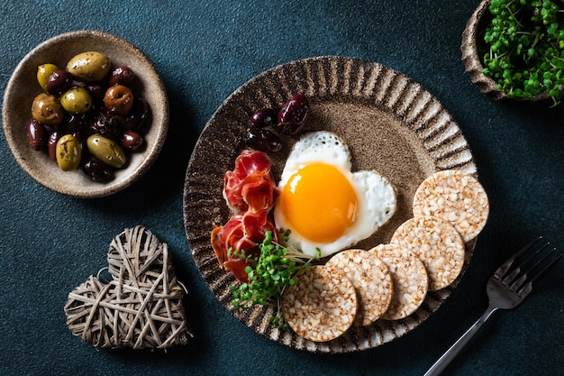 Breakfast on Women's Day - fried eggs in the shape of a heart and olives. Healthy breakfast. Rice cakes with eggs and hamon. Romantic breakfast. Top view.