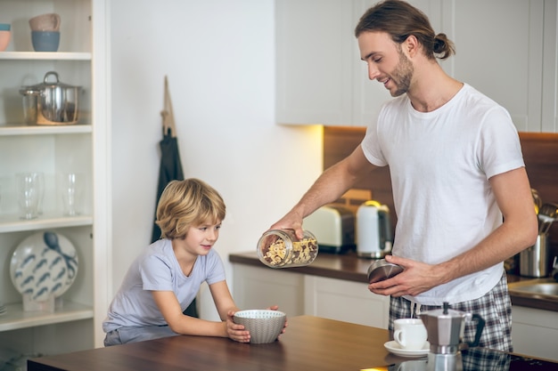 Prima colazione. giovane uomo in homewear facendo colazione per suo figlio