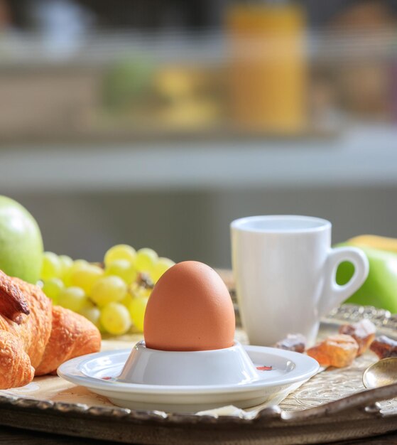 Foto colazione servita frutta fresca croissant uovo in tazza d'uovo e caffè su vecchio vassoio d'argento