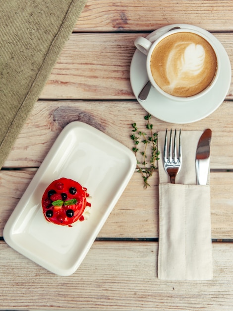 Foto breakfest met cappuccino en cake op houten tafel met vork en mes