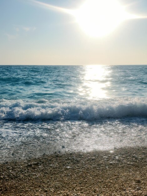 小石のビーチの青い海の砕波夏の背景