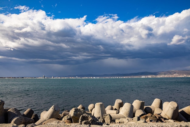 Breakwater against the background of a cloudy sky and the Black Sea with waves