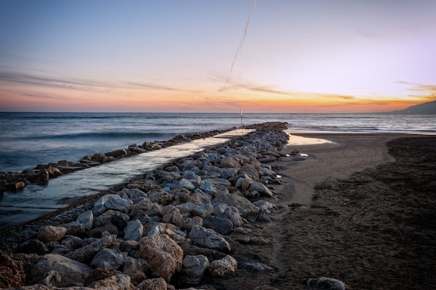 Breakwater on the beach in Malaga at sunset