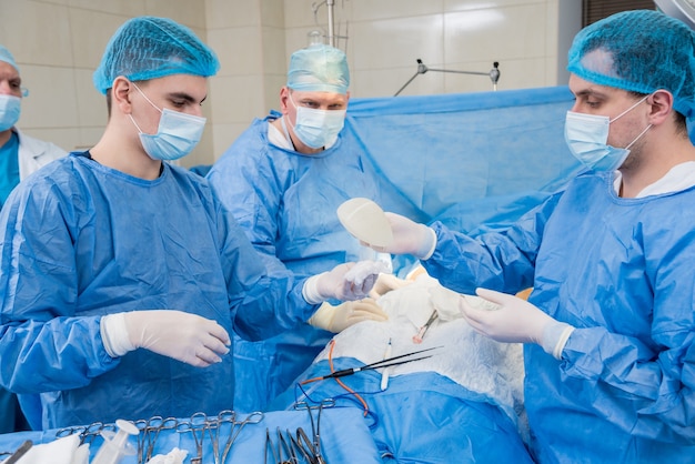 Увеличение груди под руководством команды хирургов в хирургической операционной