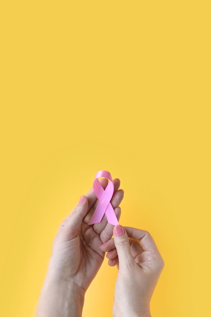 Осведомленность о раке груди "Я есть и буду" Руки женщины, держащей розовую ленту Всемирный день борьбы с раком