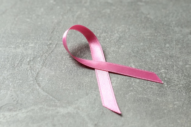 Breast cancer awareness ribbon on gray textured background