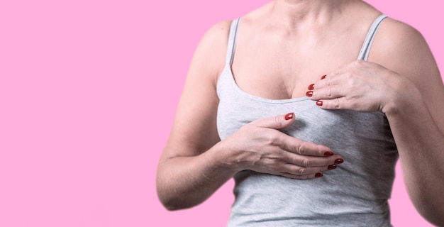 Foto breast cancer day een jonge vrouw controleert haar borsten op een gekleurde achtergrond cancer awareness concept