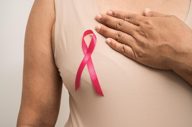 Розовая лента рака молочной железы на азиатской пожилой женщине за поддержку символа осведомленности о Всемирном дне рака молочной железы