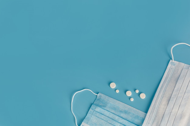 Breathing mask and pills on blue background