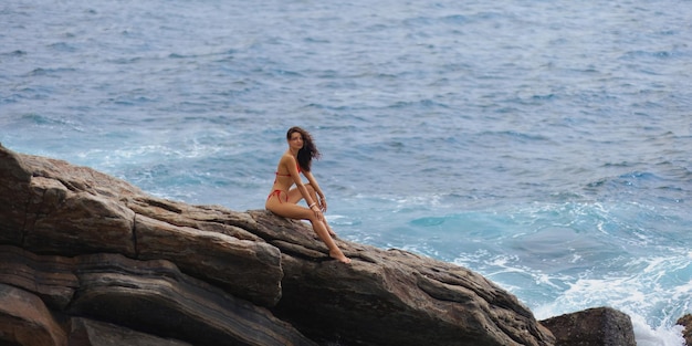 Breathtaking aerial scene of woman model in bikini on seaside cliffs