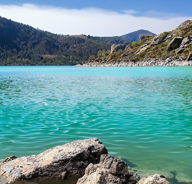 breathtaking shot of beautiful stones under the turquoise water of a lake and hills in the backgroun