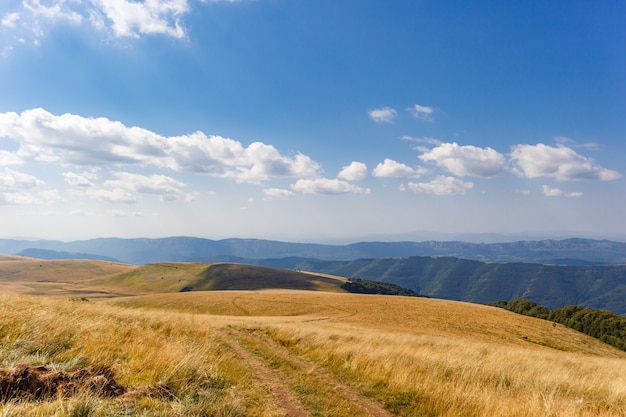 Vista mozzafiato di una valle di montagna sotto un cielo nuvoloso blu all'alba