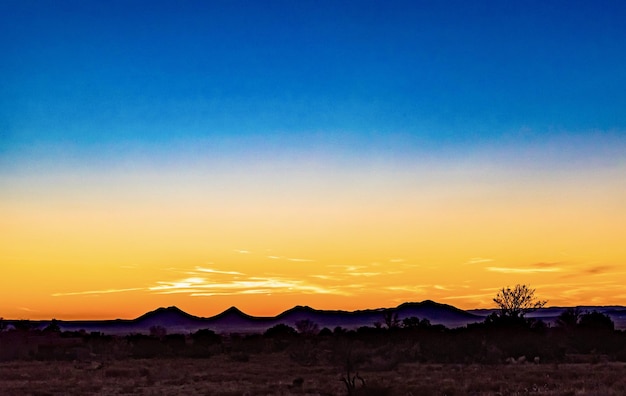 A breathtaking view of an orange and blue sunset sky over a field in santa fe, new mexico