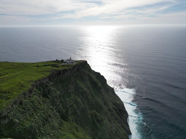 Breathtaking view of towering cliffs with lighthouse and ocean in Madeira Portugal