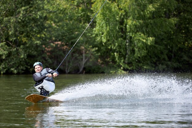 Brede hoek van jonge man met een handicap wakeboarding op het water