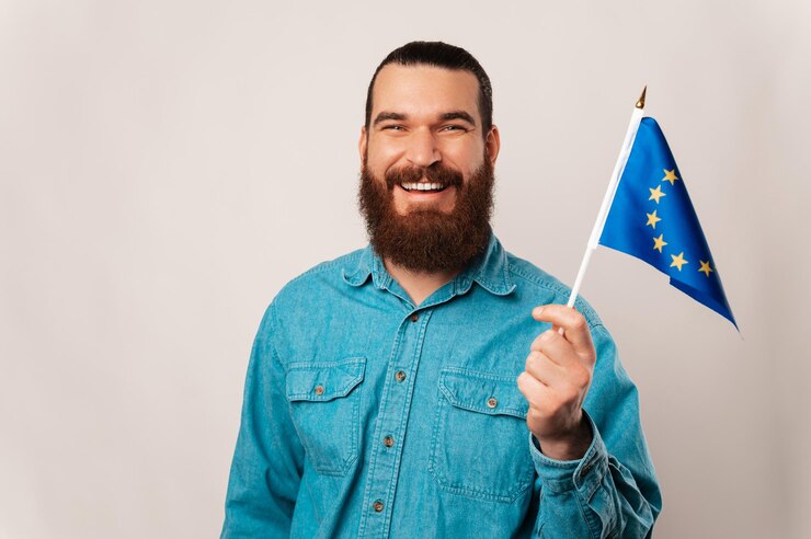 Brede lachende man zwaait met de vlag van de Europese Unie op een witte achtergrond