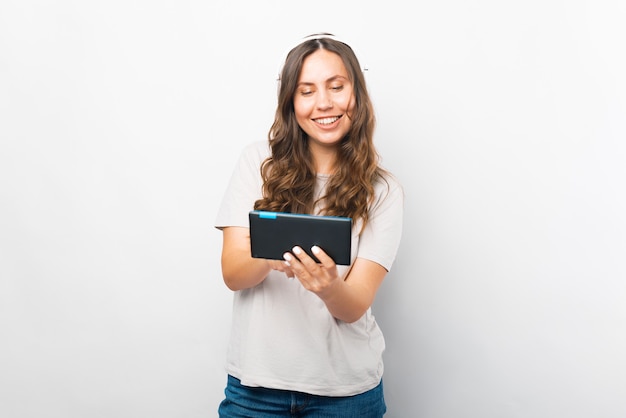 Brede lachende vrouw speelt op haar tablet terwijl ze naar de muziek luistert.