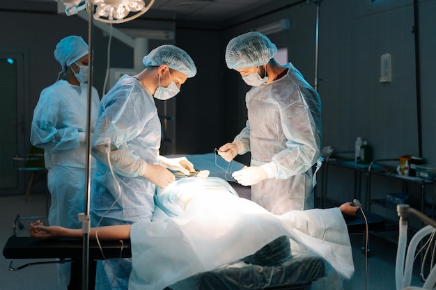 Brede opname van een divers team van professionele mannelijke chirurgen en vrouwelijke verpleegsters die invasieve chirurgie uitvoeren