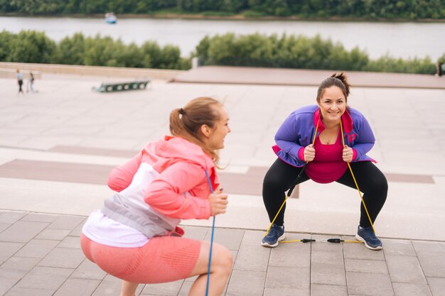 Brede opname van jonge vrouw met overgewicht die squatsoefeningen doet met fitnesstape om af te vallen met