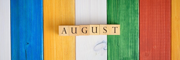 Breed beeld van houten kubussen die het woord augustus spellen over kleurrijke houten achtergrond