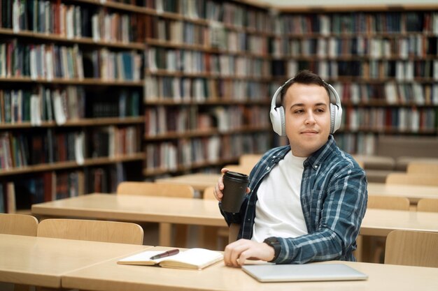 Breek een jonge mannelijke student die aan de universiteit studeert, gebruikt een videogesprek met een laptop en koptelefoon online