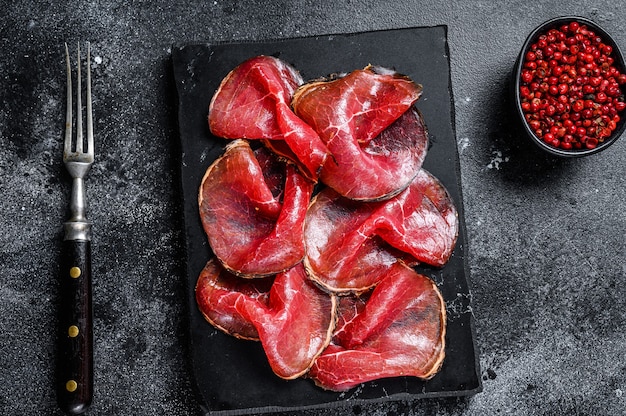 Bresaola salumi tagliata di manzo, antipasti italiani. sfondo nero. vista dall'alto.