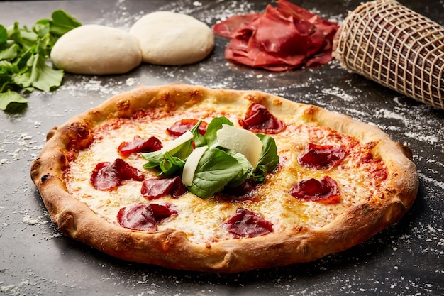 Bresaola и Rocket Pizza изолированы на темном фоне с сырой едой с верхней стороны итальянского закуски быстрого питания