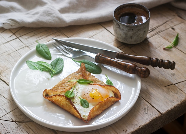 Breton buckwheat crepes with egg, spinach and cream, filed with the coffee. Rustic style.