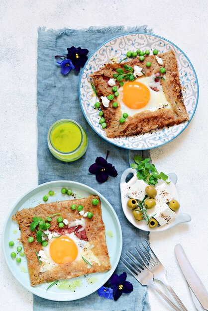 Breton traditional pancake made from buckwheat flour with ham, cheese, egg, feta, green peas and green butter.