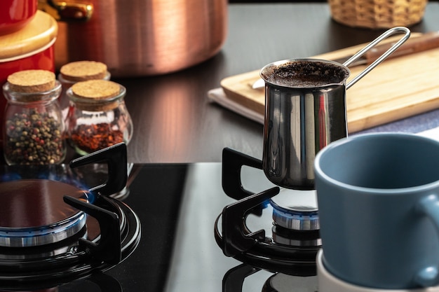 Brew coffee in a steel turk on a gas stove close up