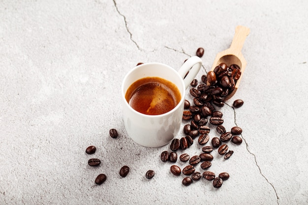 Brewed espresso coffee in a white mug on concrete background