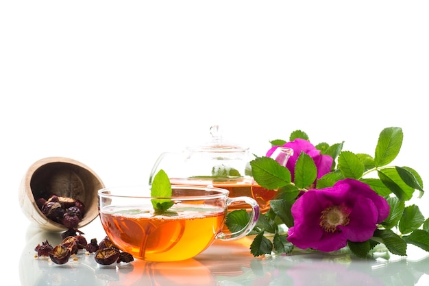 Заварной чай из шиповника в стеклянном чайнике с цветками шиповника и мятой