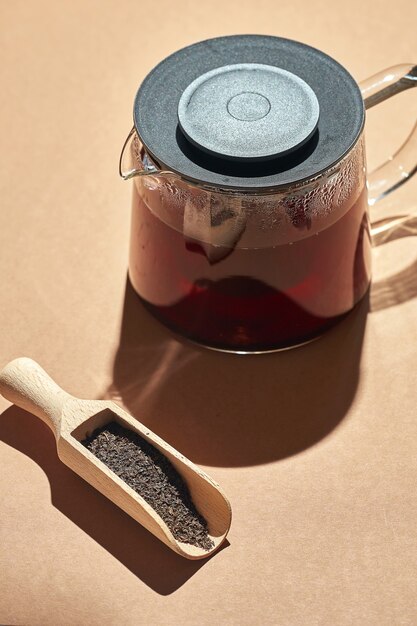 Brewed tea in a glass teapot on a brown background. Turkish tea in a wooden spoon