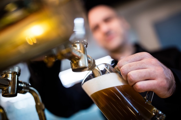 Foto birraio riempiendo la birra nel bicchiere da birra dalla pompa della birra