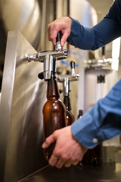 Foto birraio riempiendo birra in bottiglia