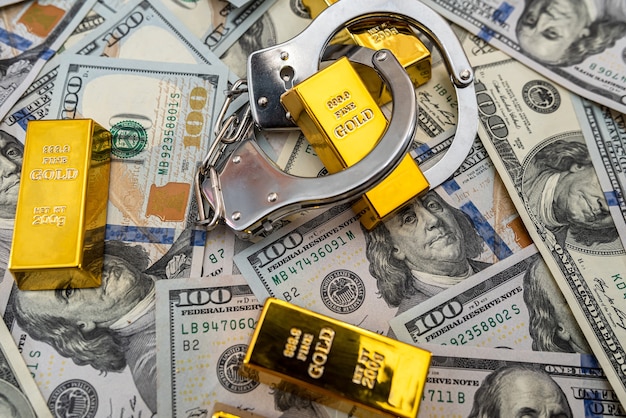 Bribe concept gold bars and handcuff in dollar bills