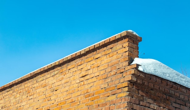 Brick brown old wall covered with snow